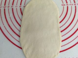 6、热狗面包,取一个松弛好的面团,擀成椭圆形的面片。