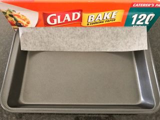 16、三文鱼奶酪菠菜蛋卷,烤箱预热180度，我们再来准备烤盘，在烤盘上面铺盖一张烤纸，