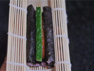 14、花朵寿司——小朋友最爱哦,用手将寿司帘托起来，轻轻将寿司捏紧，两条寿司中间的空隙处放上一根黄瓜条