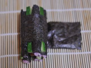 17、花朵寿司——小朋友最爱哦,将寿司帘打开一条缝，在寿司条下面摆放一片长方形海苔，轻轻转动帘子，将寿司裹起来成花瓣状