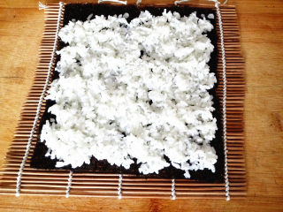 5、幸福的紫菜包饭,紫菜平铺在寿司卷帘上，上面铺上米饭，注意一定要均匀，这样做出来的寿司才漂亮