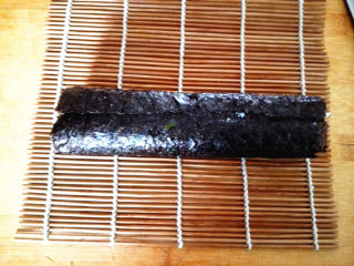 7、幸福的紫菜包饭,用寿司帘将其卷起，注意要卷得紧一些，这样切出来的寿司才漂亮，