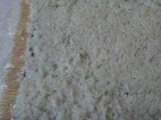 3、三文鱼寿司,寿司竹帘上平铺一层厨用薄膜，放上海苔后，将米饭适量在海苔上铺平