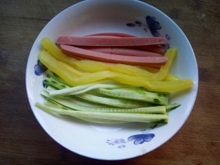 2、樱花寿司,煮饭的时间来准备配料，分别将火腿肠、萝卜发根、黄瓜切细条。