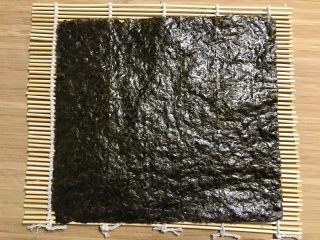 2、快手紫菜包饭,寿司帘上铺上紫菜。