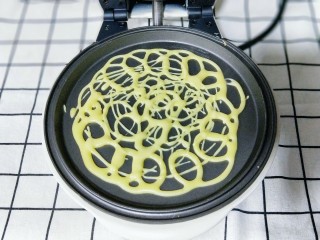 10、网红蕾丝蛋卷#华夫饼机器版#,将面糊不规则的画圈挤在华夫饼机器的烤盘上约1分钟面糊凝固即可，#注意蕾丝蛋卷的密度要适度，太稀疏会断开，太密也会影响成品的美观及口感。#