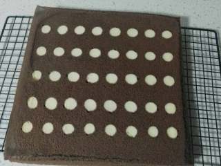 11、波点巧克力蛋糕卷,倒扣在晾网上，撕去硅胶垫，晾凉，（如果是新手的话，等蛋糕还有一点点余温时，可以用油纸先卷起定型，等凉后再打开夹奶油，这样不容易卷裂）