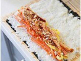 7、韩式紫菜包饭,在靠自己的这一头，铺上黄瓜、 胡萝卜、韩式泡菜、鸡蛋、火腿 条，撒上杏仁碎。