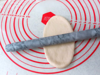 6、经典软餐包【黄油面包卷】,将松弛好的面团擀开成椭圆形