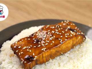 5、烤箱版红烧鱼盖饭,将烤好的三文鱼盖在米饭上,撒上熟白芝麻,淋上酱料