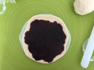 8、圣诞雪花面包,松弛好的面团按扁,擀成6寸大的圆,放在一张8寸的圆形油纸上,然后圆面皮上均匀抹上红豆沙馅