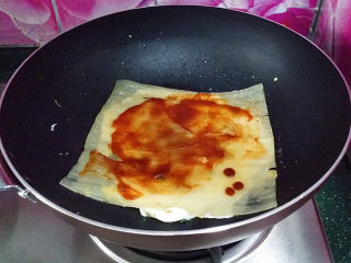 6、烤冷面,待蛋液快要凝固时及时翻面、抹上番茄酱和冷面酱