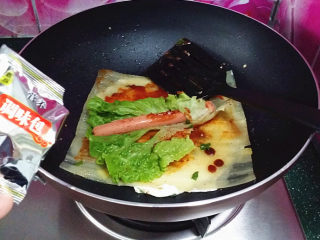 7、烤冷面,接着放生菜、火腿肠，再撒些自配调料