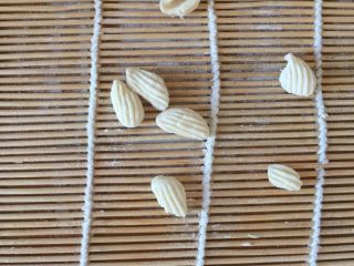 5、红烧贝壳面,拿做寿司????的卷席将刚刚的切成条的面、揪拇指大一块儿在席子上拿大拇指推压就是一个个小贝壳面了。