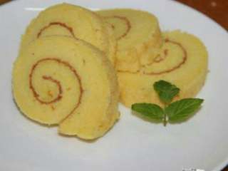 9、美味蛋糕卷,下面铺一张油纸，开始像卷寿司一样用擀面杖卷起。切块，装盘。