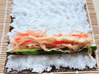 10、紫菜包饭,黄瓜条，鱿鱼丝依次放上，喜欢吃鱿鱼丝的小伙伴也可以多放一些