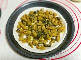 20、做饼＋咖喱香菇鸡丁披萨饼,首先将披萨皮上面撒一层马苏里拉芝士，再将做好的咖喱鸡丁放在披萨皮上。