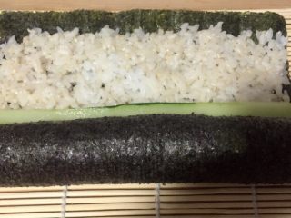18、酱香味秋葵寿司(纯素版),打开竹席放一根黄瓜条,用竹席继续卷