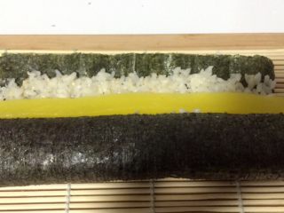 19、酱香味秋葵寿司(纯素版),打开竹席放一根大根,继续用竹席卷上,并用力