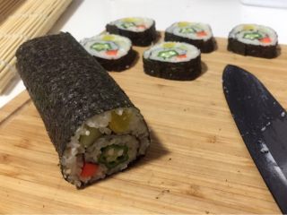 21、酱香味秋葵寿司(纯素版),打开竹席,取出海苔饭卷,用刀沾水,然后切成段,漂亮的五角秋葵就露出来啦