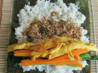 5、水滴寿司,海苔放在寿司卷帘上，铺上一层米饭，放入鸡蛋皮，胡萝卜，菠菜再撒上味岛香松。