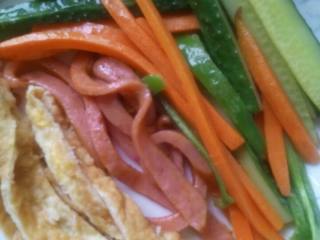 2、紫菜包饭,鸡蛋中加入少量淀粉，锅中放入油，油热后，将鸡蛋煎成饼后，切成条。将准备好的食材翻入热油的锅中，加少量盐炒几下。