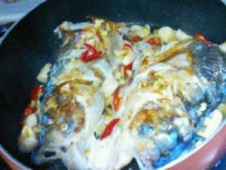 5、自制【鱼头豆腐火锅】,鱼头煎至好了，把姜，蒜，红尖 椒放入。