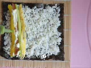 9、基础寿司,当然也可以这样不铺保鲜膜，米饭尽量不要压实。然后在靠近自己这一端的米饭上放上火腿肠、黄瓜、大根条、沙拉酱、青芥辣。