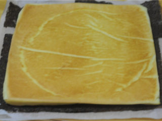 9、紫菜肉松蛋糕卷,蛋糕微微还有点热的时候，就可以卷了，将两片紫菜放在蛋糕片下面