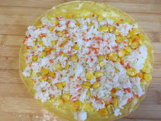 9、早餐鸡蛋卷,将煎好的蛋饼放在案板上,表面铺上什锦饭,用手将什锦饭压一下。