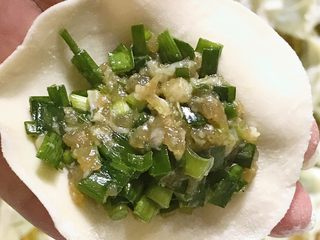 23、年夜饭+韭菜猪肉馅饺子详解,手托住一张饺子皮，放上馅料。