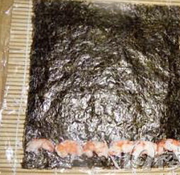 4、黄袍加身寿司,再铺上一层寿司紫菜，在前端放上虾仁