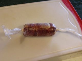 5、 鮟鱇鱼生火腿佐芒果酱汁,用生火腿片将鱼肉卷起。再用保鲜膜将火腿鱼肉卷起，两边紧紧打结。将卷好的鱼肉卷放冰箱冷藏30分钟以上，让它定型。