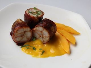 8、 鮟鱇鱼生火腿佐芒果酱汁,切段摆盘，铺上芒果酱洒一些香草叶，趁热上桌。鱼肉口感结实有咬劲跟一般鱼肉不太一样，风味介于鸡肉和龙虾之间，包覆在外的生火腿丰富的油脂和鱼肉搭