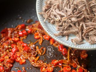 12、麻辣手撕牛肉,倒入撕好的牛肉下去翻炒至牛肉丝全部裹上酱料，变成深红色为止;