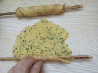 14、黑芝麻蛋卷，十分钟搞定早餐,在做好的蛋饼上放一根筷子，轻轻用手卷起。
