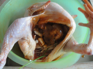 6、奥尔良烤鸡,把香菇、金针菇、小葱塞进鸡肚里再把盆里的料汁加入一点进去