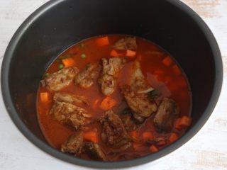 11、酱香排骨焖饭,将排骨连同汤汁一起倒入电饭锅中。注意排骨汤汁的量就是平时挣米饭加水的量。