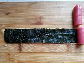 9、年夜菜~锦绣苔味香肠卷,然后把台味香肠切成与海苔同宽的小段，摆在海苔上