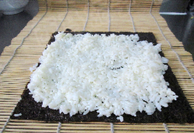 2、金艳果沙拉寿司,将寿司紫菜放在寿司帘子上，搅拌好的米饭铺在紫菜上面压实