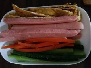 4、金枪鱼寿司,然后把鸡蛋和香肠切成条。胡萝卜和黄瓜切条后用水焯一下水里也放点盐。摆好备用。