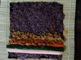 7、金枪鱼寿司,配料准备好后包就快了。把紫菜摆好铺上一层米。把鸡蛋香肠准备好的配料都摆上。