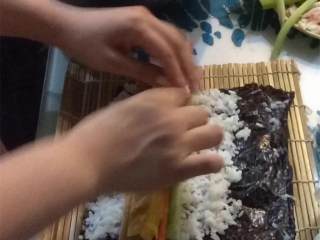 9、紫菜包饭（韩式寿司）,把竹帘和紫菜片 放在你面前的桌上。舀一杯米饭铺在紫菜片上，大约占2/3大小，紫菜片空出一侧不铺米饭。