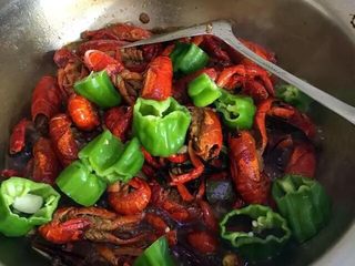21、啤酒麻辣小龙虾,打开锅盖放入盐和蒜瓣，翻炒均匀后，再次盖上锅盖焖煮5分钟。5分钟以后揭开锅盖，开大火放入青椒筒。翻炒至青椒变色后，关火。