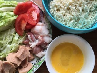 3、沙茶酱炒面#面条变身计划#,将包菜切丝，肉切成薄片，西红柿切片，午餐肉用勺挖小块。锅里烧开水后把面片放入焯烫变软后捞出沥干水份备用。鸡蛋打散后备用。