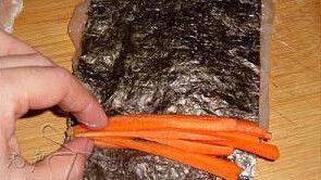 3、如意鸡肉卷,放上半张寿司海苔,再放上一些胡萝卜丝，紧紧地卷起来，扎好