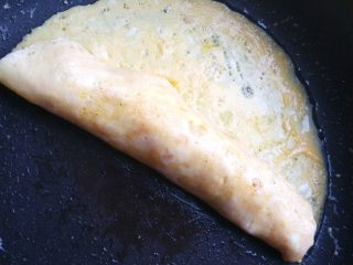 4、紫菜蛋包饭,用木铲辅助，将一边的蛋饼翻过来包住炒饭，压紧