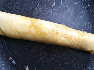 5、紫菜蛋包饭,继续卷动蛋饼，把整个米饭包成长条，接口在底部