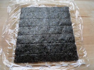 4、花朵寿司,寿司帘上放保鲜膜，放一片紫菜。