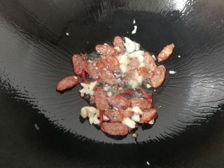 7、腊肠手撕包菜,接着放入花椒，干红辣椒，蒜末煸出香味；